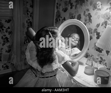 1950s LITTLE GIRL POSING REFLECTED IN MIRROR AT VANITY TABLE Stock Photo