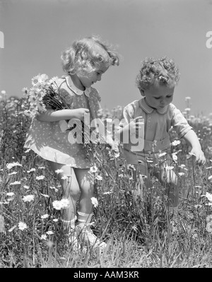 1940s BOY & GIRL PICKING DAISIES Stock Photo