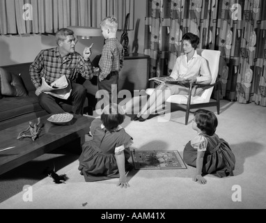 1960s FAMILY OF FOUR IN LIVING ROOM BOY IS BEING DISCIPLINED BY DAD SHAKING FINGER Stock Photo