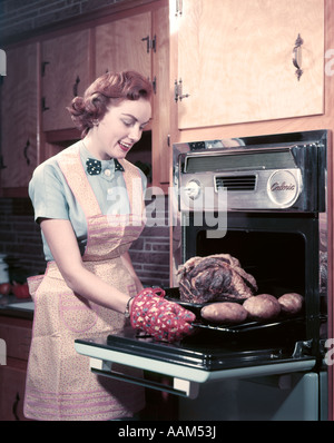 https://l450v.alamy.com/450v/aam53j/1950s-smiling-woman-housewife-wearing-apron-and-oven-mitts-taking-aam53j.jpg