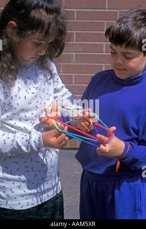 BOY AND GIRL PLAYING YARN HAND GAME "CATS IN THE CRADLE" Stock Photo