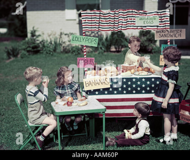 1940s GIRLS AND BOYS IN BUSINESS WITH A LEMONADE AND FAST SNACK FOOD STAND ON THE 4TH OF JULY AMERICANA NOSTALGIA Stock Photo