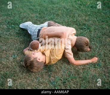 TWO BOYS WRESTLING PLAYING FOOTBALL TACKLE ON LAWN Stock Photo