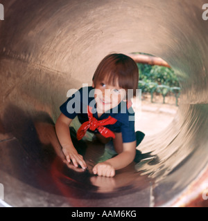 BOY PLAYING IN PIPE SLIDE AT PLAYGROUND Stock Photo