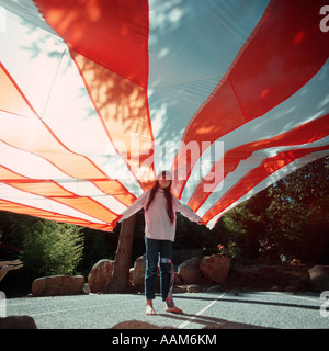 GIRL HOLDING ORANGE AND WHTE PARACHUTE Stock Photo