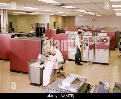 1960s TWO MEN IN OFFICE WORKING AT MAINFRAME REEL TO REEL COMPUTERS Stock Photo