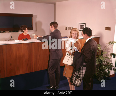 1960 1960s THREE PEOPLE IN LINE WAITING FOR BANK TELLER CASHIER