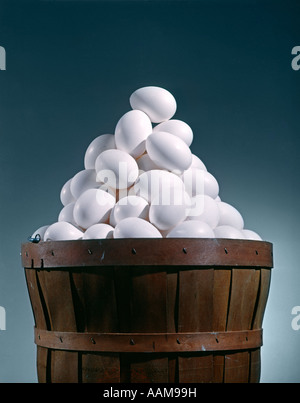 BROWN WOODEN BUSHEL BASKET FULL OF WHITE CHICKEN EGGS IN 1 BASKET PYRAMID SHAPE TRIANGLE Stock Photo