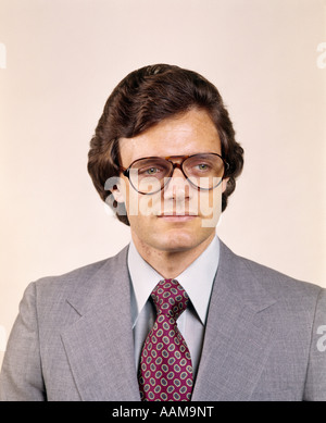 1970s MAN PORTRAIT BUSINESS SUIT SERIOUS EXPRESSION AVIATOR EYEGLASSES FASHION RETRO Stock Photo