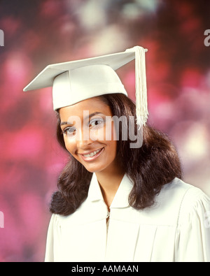 1970 1970s ETHNIC AFRICAN-AMERICAN WOMAN GIRL TEEN SMILE SMILING WEAR WHITE ROBE MORTAR BOARD GRADUATE GRADUATION Stock Photo