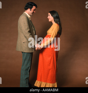 COUPLE MAN AND PREGNANT WOMAN STANDING FACING EACH OTHER HOLDING HANDS Stock Photo