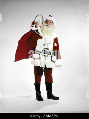 1960s FULL LENGTH PORTRAIT OF SANTA CLAUS WITH STUFFED TOY SACK ON HIS BACK STUDIO Stock Photo