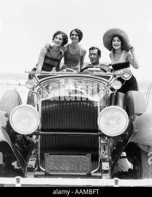 1920s 1930s MAN DRIVING CONVERTIBLE TOURING CAR WITH THREE WOMEN IN BATHING SUITS AS PASSENGERS Stock Photo