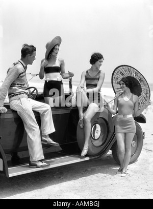 1920s 1930s MAN AND THREE WOMEN IN BEACH CLOTHES OR BATHING SUITS POSING WITH CAR ON RUNNING BOARD Stock Photo
