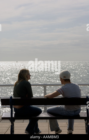 young couple man and woman sitting and talking on the promenade in Aberystwyth with Cardigan Bay behind them summer afternoon Stock Photo