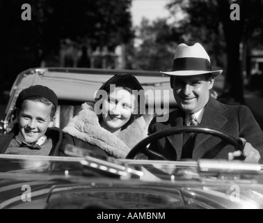 1930s SMILING FAMILY PORTRAIT MAN FATHER WOMAN MOTHER BOY SON RIDING IN CONVERTIBLE AUTOMOBILE Stock Photo