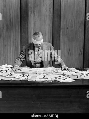 1940s BLINDFOLDED MAN IN OFFICE POST WAR SIGN ON DESK Stock Photo