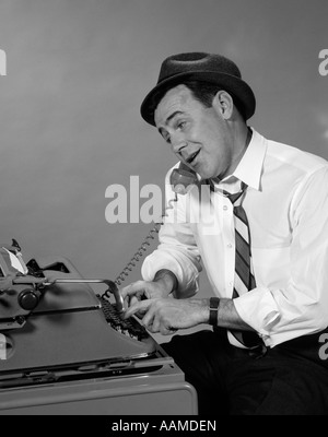 1960s REPORTER WITH HAT ON PHONE AT TYPEWRITER Stock Photo