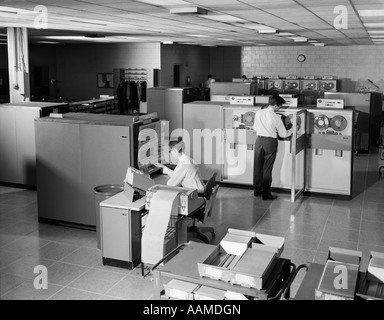 1960s TWO MEN TECHNICIANS WORKING IN IBM 360 MAINFRAME COMPUTER ROOM Stock Photo