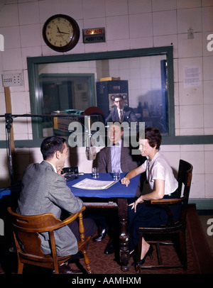 1960s COLLEGE RADIO STATION DJ INTERVIEW MAN & WOMAN AROUND MICROPHONE AT TABLE ON AIR SIGN CONTROL ROOM BROADCASTING Stock Photo