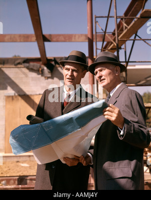 TWO MEN WITH BLUEPRINTS AT CONSTRUCTION SITE Stock Photo