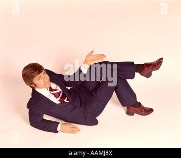 1970 1970s OVERHEAD LOOKING DOWN MAN LYING DOWN LEGS CROSSED WEAR BUSINESS SUIT SHRUG OFF HAND EXPRESSION GESTURE Stock Photo