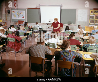 1960s TEACHER WITH CLASS IN SCHOOLROOM WITH AUDIO VISUAL MACHINE EQUIPMENT Stock Photo