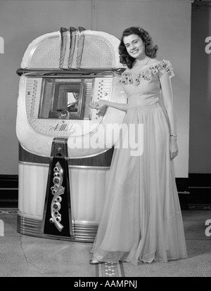 1940s PORTRAIT OF WOMAN IN BALL GOWN IN FRONT OF JUKEBOX Stock Photo