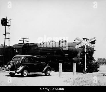 1930s CAR STOPPED AT RAILROAD CROSSING WITH FREIGHT TRAIN SPEEDING BY Stock Photo