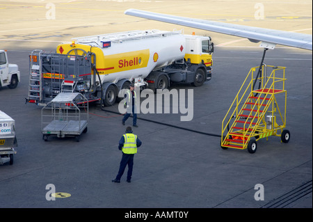 shell aircraft fuel tanker driver approaches refuelling rig as ground crew watches refuelling a boeing 757 on the apron Stock Photo