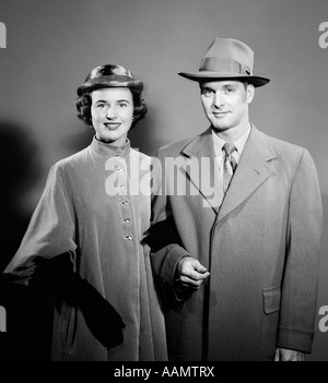 1940s 1950s COUPLE MAN WOMAN SIDE BY SIDE WEARING OUTDOOR CLOTHING COATS & HATS LOOKING AT CAMERA Stock Photo