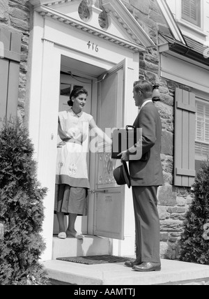 1950s SALESMAN AT DOOR TALKING TO HOUSEWIFE Stock Photo