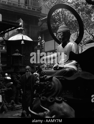 1930s ELDERLY SENIOR JAPANESE MAN IN KIMONO WALKING AMIDST SCULPTURE & BUDDHA STATUE IN KOBE CURIO SHOP JAPAN Stock Photo