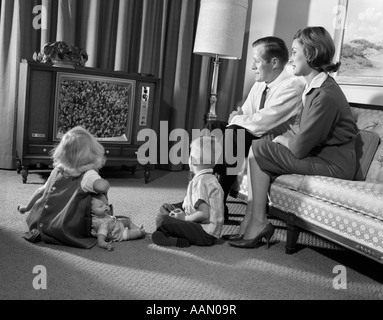 1960s FAMILY MOM DAD & 2 KIDS STANDING IN YARD BY HOUSE Stock Photo