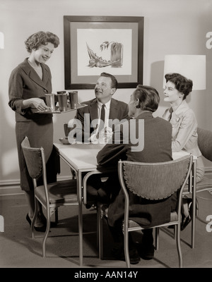 1950s CARD PARTY OF 2 COUPLES WITH WOMAN SERVING DRINKS Stock Photo