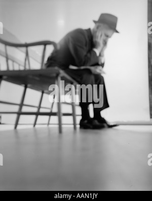1960s DEPRESSED ELDERLY MAN SITTING ON BENCH LEANING FORWARD ELBOWS ON KNEES HEAD IN HANDS Stock Photo