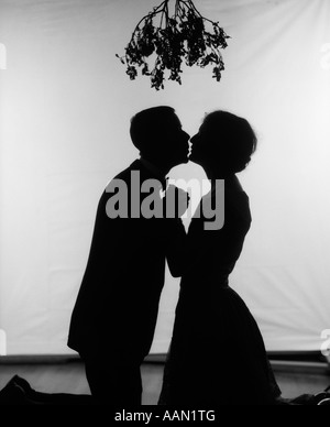 1920s SILHOUETTE OF COUPLE KISSING UNDER MISTLETOE Stock Photo