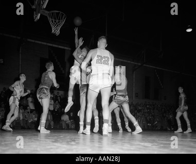 1950s BOYS' BASKETBALL GAME INDOORS BOY JUMPING Stock Photo