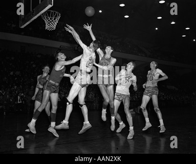 1950s COLLEGE BASKETBALL BALTIMORE WARRIORS PHILADELPHIA BALL IS IN AIR PLAYERS JUMPING UNDER HOOP Stock Photo