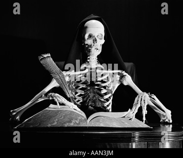 STILL LIFE OF SKELETON WRITING IN LARGE BOOK WITH QUILL PEN Stock Photo