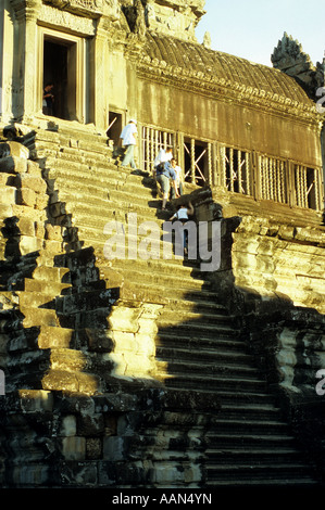 Tourists climbing up very steep stone steps to upper level towers, late afternoon, Angkor Wat Temple, Cambodia Stock Photo