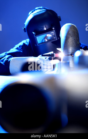 Welder welding stainless steel pipework on a work bench Stock Photo