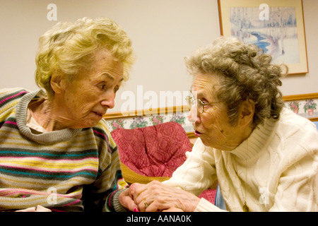 Sisters age 92 trying to communicate and holding hands in nursing home. Minnesota Masonic Home Bloomington Minnesota USA Stock Photo