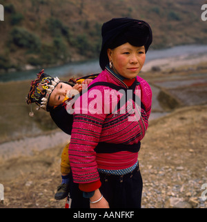 A waist-high photo of Yao Tribe woman carrying child on her back in Longsheng Autonomous Region in Guangxi Province China Stock Photo