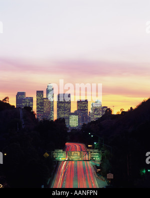 Retro image Sunset over LA Downtown District with skyscrapers with car light trails and Highway 110 Los Angeles California USA Stock Photo