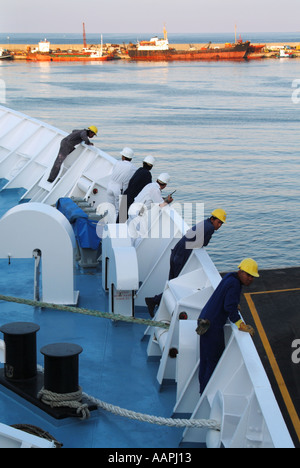 Crew and officers on cruise ship leaning over bow to check dockside preparations for departure Stock Photo