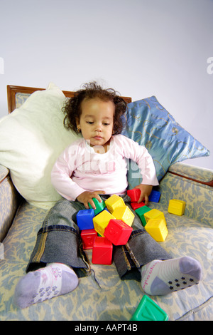 Young baby toddler aged sat on a chair with learning blocks