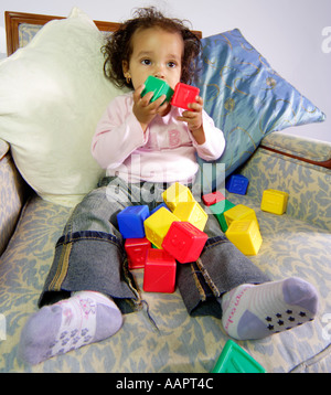Young baby toddler aged sat on a chair with learning blocks