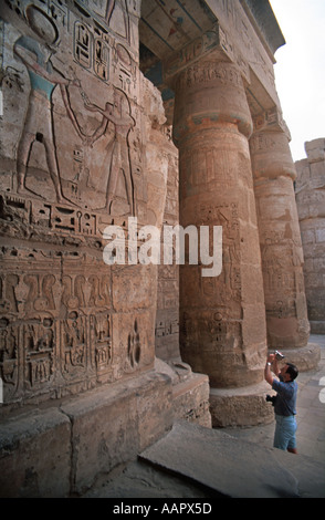 The site of Medinet Habu Thebes Egypt Columns and reliefs in the second courtyard being recorded on video camera by a tourist Stock Photo