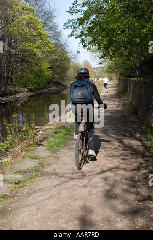 Cyclist on tow path besdie Huddersfield Narrow Canal at Slaithwaite Stock Photo